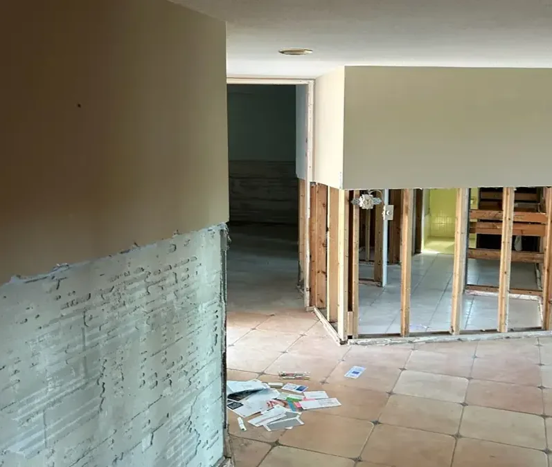 Lower drywall removed above a tile floor to expose wet wall framing