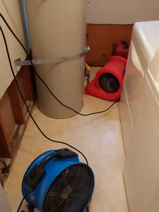 Air movers dry an opened wall behind laundry appliances