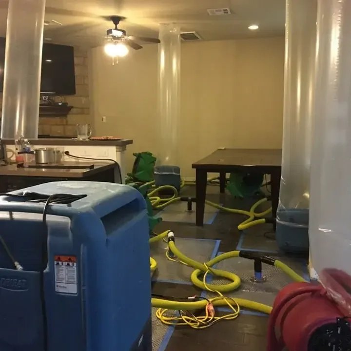 Air movers and a dehumidifier stand on a kitchen floor during drying.