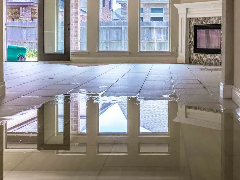 Standing water covers a tiled room floor beside glass doors and exposed lower walls