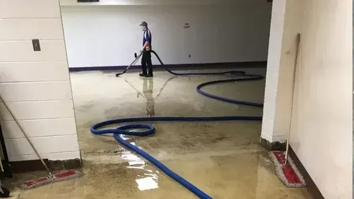A technician draws an extraction wand through standing water inside a building